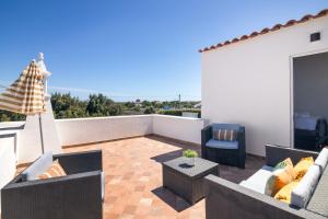 a patio with couches and chairs on a balcony at Vilas Salero in Moncarapacho