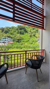 a balcony with two chairs and a large window at Alura Boutique in Kata Beach