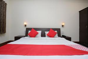a bedroom with a large bed with red pillows at Hotel O Crown Hidden Residency in Satna