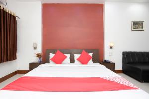 a bedroom with a large bed with red pillows at Hotel O Crown Hidden Residency in Satna