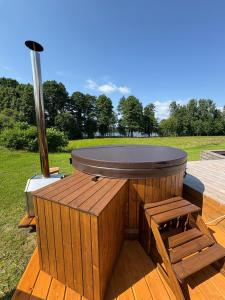 a hot tub sitting on a deck with two benches at Rātes Krasti - Rasa - holiday house with sauna and lakeview in Lejasciems