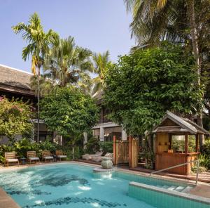 a swimming pool in front of a building with trees at Maison Dalabua in Luang Prabang