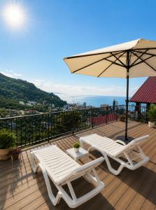 zwei Liegestühle und ein Sonnenschirm auf einem Deck in der Unterkunft Ramgon in Gonio