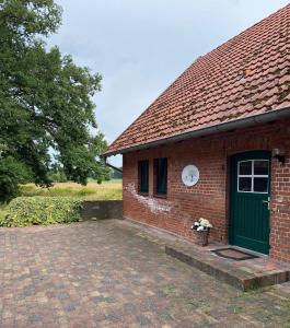 a brick building with a green door and a clock at Smeers Hof in Böhme
