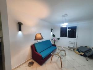 a living room with a blue chair and a lamp at la vue coucher de soleil in Hauara