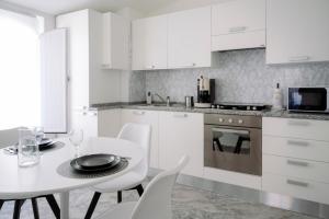a white kitchen with a white table and chairs at The Square - Luxury Apartment in Scilla