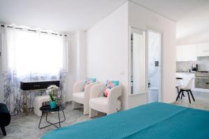 a white bedroom with a blue bed and chairs at The Square - Luxury Apartment in Scilla