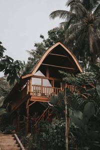 a wooden house with a deck in the jungle at Kusfarm Bali by AHM in Selemadeg