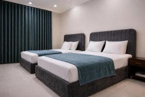two beds in a hotel room with black curtains at Studio 13 in Islamabad +28 photos