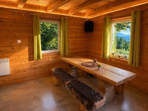 a wooden room with a wooden table and two windows at Hiška Miru Peace Cabin in Mozirje