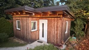 a wooden shed with a door in a yard at Hiška Miru Peace Cabin in Mozirje