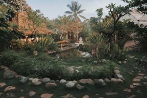 a garden with a pond in front of a house at Kusfarm Bali by AHM in Selemadeg