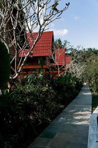 a building with a red roof next to a walkway at Kusfarm Bali by AHM in Selemadeg