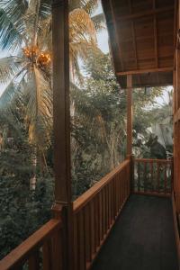 a porch of a house with a palm tree at Kusfarm Bali by AHM in Selemadeg