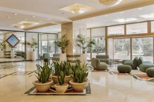 a lobby with potted plants in the middle at Divani Apollon Palace & Thalasso in Athens +48 photos