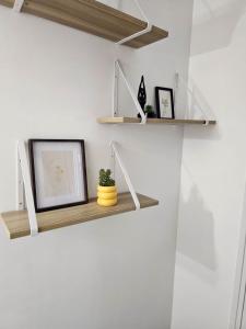 a shelf on a wall with two pictures and a plant at Cozy haven in Venise Provençale in Martigues +3 photos