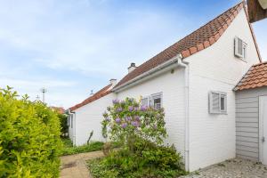 a white house with a garden and purple flowers at Sea Side Village 91 in De Haan