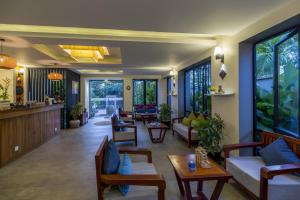 a living room with couches and tables and windows at Indra Angkor Hotel in Siem Reap