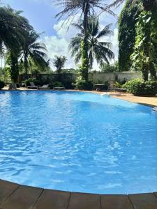 a large blue swimming pool with palm trees in the background at Vacation by the ocean in Phuket
