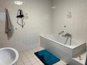 a white bathroom with a tub and a sink at Wohnen am Rande des Schwarzwaldes in Eggingen
