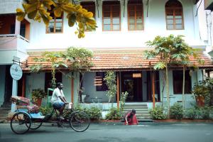 a man riding a bike in front of a building with a dog at Maison Perumal Pondicherry - A CGH Earth Experience in Puducherry