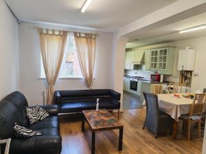 a living room with a black leather couch and a table at Spacious Double Room with Shared Bathroom in London
