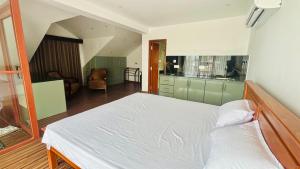 a bedroom with a white bed and a kitchen at SB Guest in Trincomalee