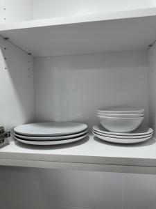 a stack of plates and bowls on a shelf at Morden suite in Surrey