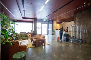 a lobby with couches and chairs and people standing in a room at Zara Tower – Luxury Suites and Apartments in Sydney