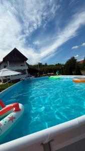a large blue swimming pool with a house in the background at Casa Dumbrăvița in Sibiu