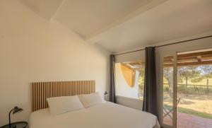 a bedroom with a white bed and a window at L'Oustau des Palunettes Concept Adulte only in Saintes-Maries-de-la-Mer