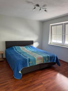 a bedroom with a bed with a blue comforter and a window at Ferienwohnung Olpe in Olpe