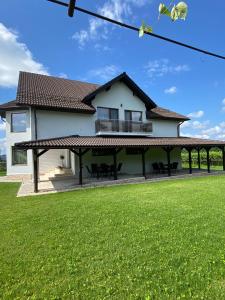 a house with a large yard with green grass at Alpine Grace Retreat in Novaci-Străini