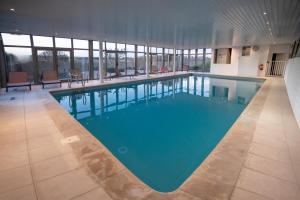 a large swimming pool with blue water in a building at Domaine Du Val in Grand-Laviers