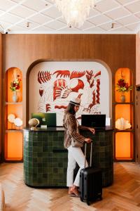 a woman standing at a counter with her luggage at Posidonia Hôtel in Nice