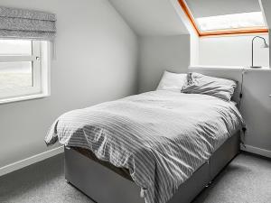 a bed in a white room with a window at The Anchorage in Collieston +8 photos
