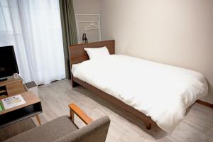 a bedroom with a bed and a chair and a tv at リバーレインアクア in Kagoshima +7 photos