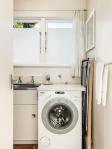 a laundry room with a washing machine and a sink at Beachfront Kiwi bach with direct beach access in Gisborne