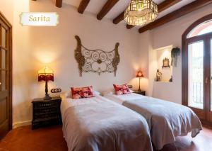 a bedroom with two beds and a chandelier at Cal Cabré del Priorat - Alojamiento y Bienestar in Pradell