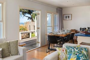 a living room with a table and chairs and a kitchen at Beachfront Kiwi bach with direct beach access in Gisborne