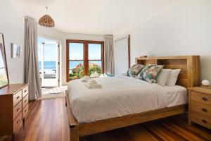a bedroom with a bed with a view of the ocean at Beachfront Kiwi bach with direct beach access in Gisborne
