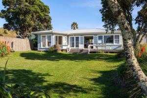a small white house with a yard at Beachfront Kiwi bach with direct beach access in Gisborne