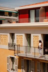 a person sitting on a balcony of a building at Posidonia Hôtel in Nice