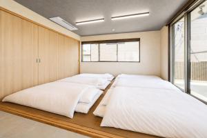 a row of beds in a room with a window at VillaMer KAWACHI in Kumamoto +23 photos