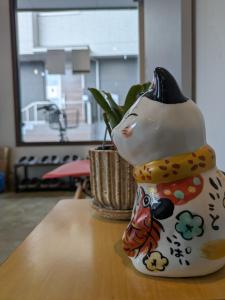 a ceramic cat figurine sitting on top of a table at Hostel x Hair ie in Hadano