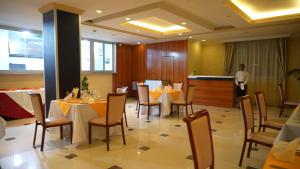 a restaurant with tables and chairs and a person standing in a room at Amdina Hotel in Mekʼelē