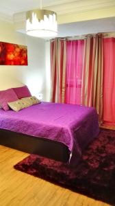 1 dormitorio con cama morada y cortinas rosas en Explanada Beach Deluxe Flat, en Alicante