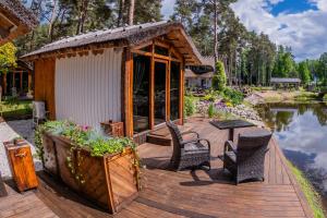 a wooden deck with chairs and a table next to a lake at Metsatiigi Resort in Kersalu