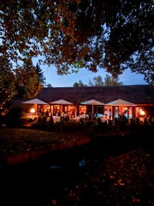 a building with tables and umbrellas at night at Hotelanlage Starick in Lübbenau