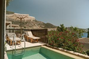 a swimming pool with two chairs and an umbrella at Asfiya Sea View Hotel in Kalkan